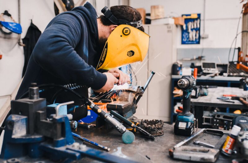 masked metal worker manipulating part