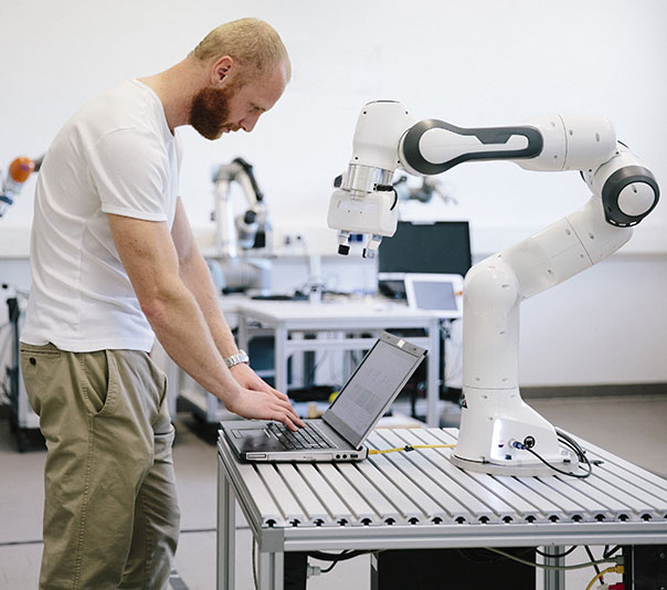 industry 4.0: Young engineer works at a robotic arm