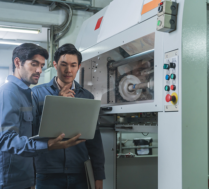 Male Asian caucasian engineer professional having a discussion standing consult at machine in the factory ,two expert coworker brainstorm explaining and solves the process of the cnc operate machine