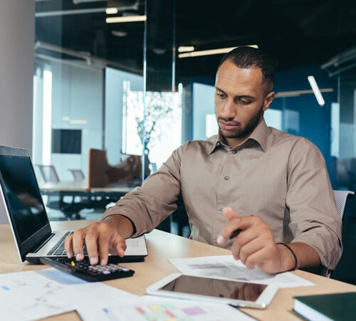 An African-American male accountant, auditor works in the office. Paper work, calculations