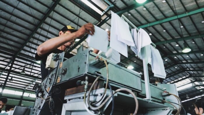 low frame shot of factory worker at his workstation checking notes