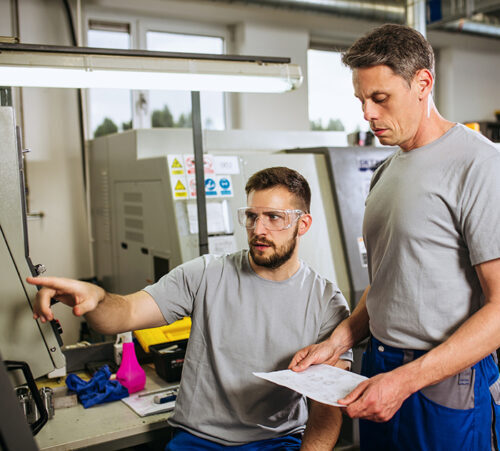 Male supervisor evaluate work in factory and writing at notepad