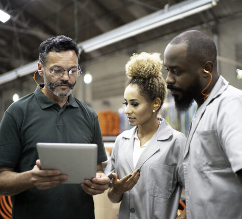 Manager showing something in a digital tablet to his employees in a factory