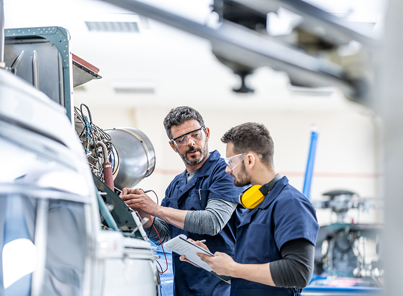 Young aviation mechanics studying to repair engine medium shot