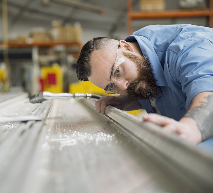 Worker examining sheet metal in manufacturing plant