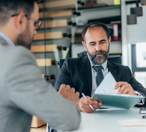 Business persons discussing new agreement. Businessman ready to sign contract at the office. Two businessmen with formal paper.