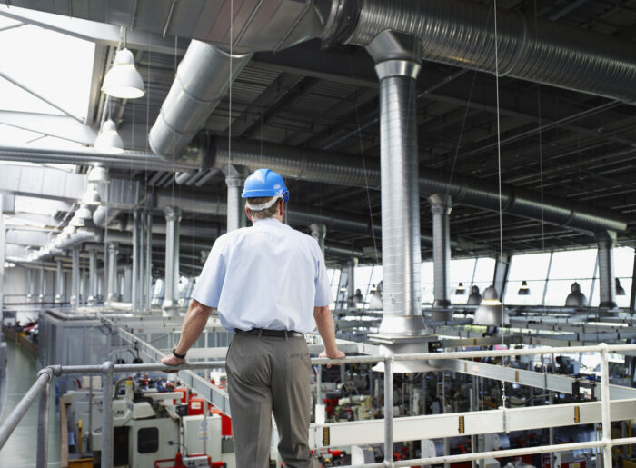 Businessman in hard-hat looking at factory floor