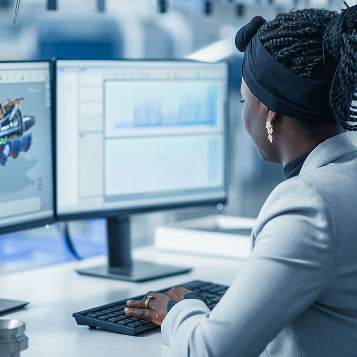 Beautiful Female Engineer Working on Personal Computer in the High-Tech Industrial Factory, She Uses CAD Software Designing 3D Turbine. Over the Shoulder Shot.