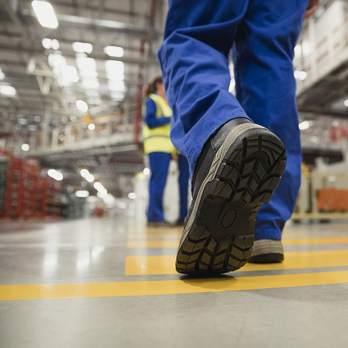 Close-up shot of a workers boot as they walk across the factory floor.