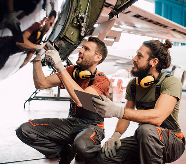 Young men repairing aircraft and using digital tablet