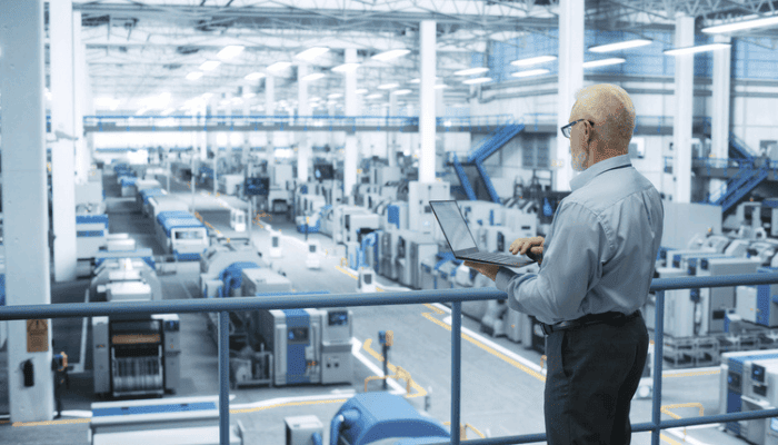 Un fabricant travaillant avec un PC portable sur le plancher de production.