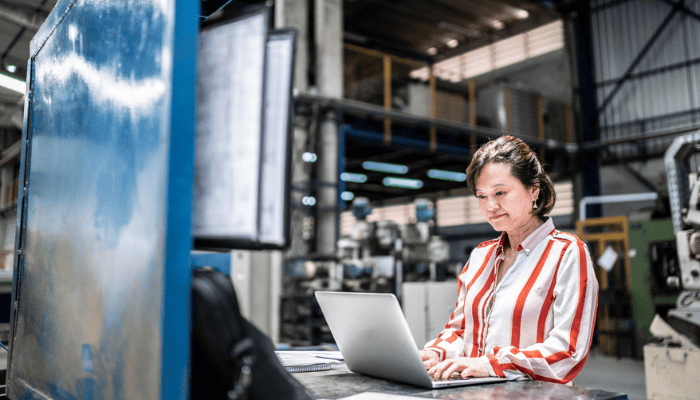 A manufacturer working on the shop floor using her laptop