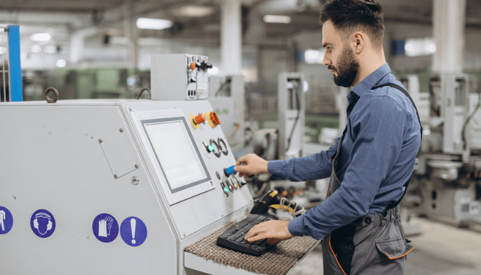 Un fabricant manipulant une machine sur le plancher de production