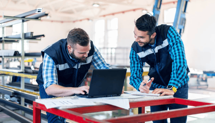Deux manufacturiers travaillant sur le plancher de production avec un ordinateur portable