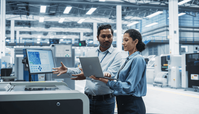 Two manufacturers working on the shop floor with a laptop