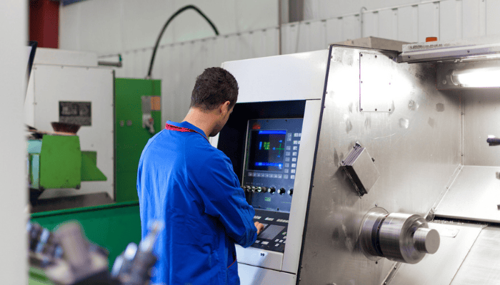 Un fabricant travaillant sur le plancher de l’atelier avec une machine.