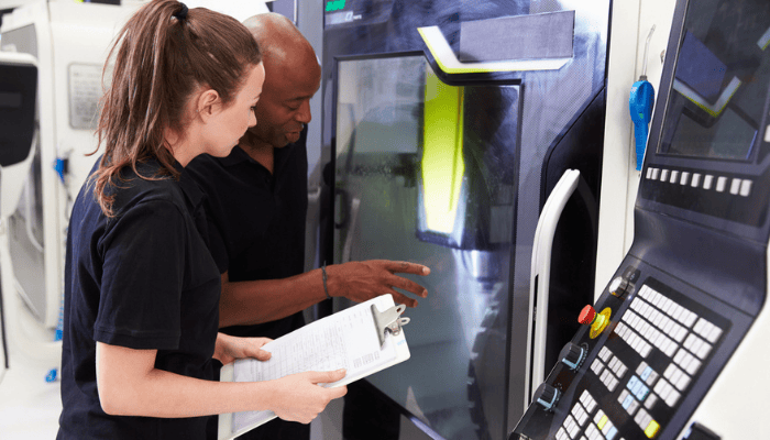 Deux manufacturiers travaillant sur une machine dans l’atelier de production